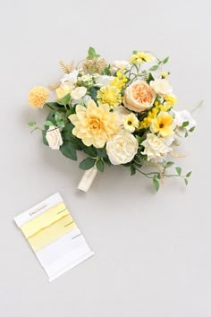 a bouquet of yellow and white flowers next to a note