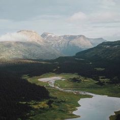 an aerial view of mountains and lakes in the distance, with clouds hovering over them