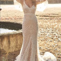 a woman in a wedding dress standing on the ground with her arms behind her head