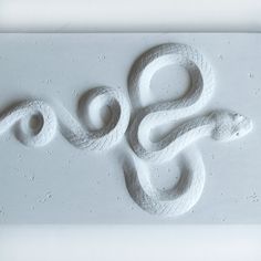 an image of a snake carved into the side of a wall or floor with water droplets on it