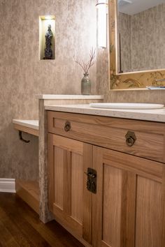 a bathroom with wooden cabinets and a white counter top under a large mirror on the wall