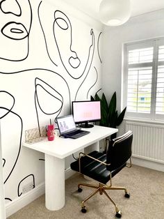 a white desk topped with a laptop computer next to a wall covered in black lines