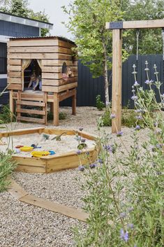 a child's play area in the backyard with sand and flowers on the ground