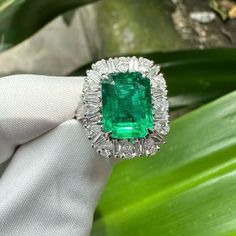 an emerald and diamond ring is being held by someone