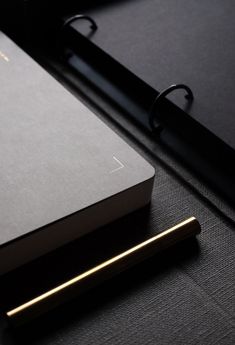 a notebook and pen sitting on top of a black surface next to an open laptop computer