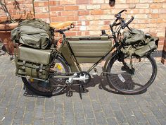 a bike with two bags on the back parked in front of a brick wall