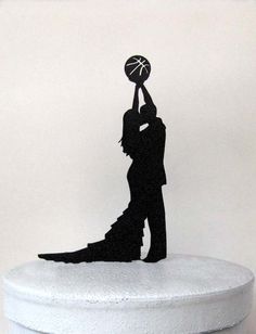 a cake topper with a silhouette of a man and woman holding a basketball above their head