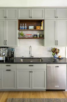 a kitchen with gray cabinets and stainless steel appliances, including a silver dishwasher