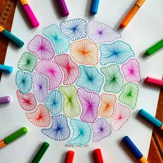 colored crayons and markers surround a drawing of an umbrellas in the center