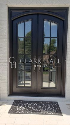 a black double door with two sidelights and a decorative mat on the outside of it