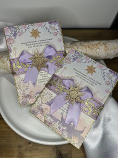 two cards with purple bows on them sitting on a plate