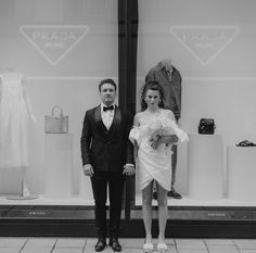 a man standing next to a woman in front of a dress shop window with mannequins