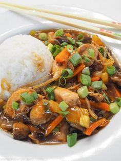 a white plate topped with meat and veggies next to rice