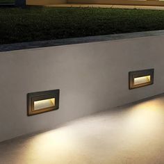 two recessed lights on the side of a wall in front of a building at night