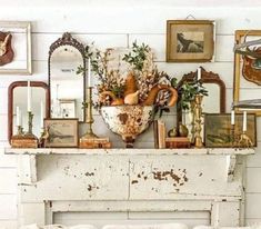 an old fireplace is adorned with antique items and flowers in vases, mirrors, and other decor