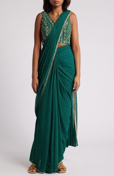 This saree has a hand-embroidered cropped top with intricate beadwork and lustrous sequins and is paired with a skirt featuring attached wraparound draping. This outfit is prestitched, so you can put it together in 30 seconds or less. V-neck Top has hook-and-eye closure; skirt has hidden side-zip closure Top and skirt feature hook-and-eye attachments for easy drape adjustments Lined 100% viscose Spot clean Made in India Asian & Pacific Islander Owned/Founded Traditional Embellished Pre-draped Saree For Festive Season, Party Wear Embellished Pre-draped Saree For Festivals, Festive Embellished Pre-draped Saree For Reception, Festive Silk Pre-draped Saree With Sequins, Festive Embellished Fitted Pre-draped Saree, Draped Georgette Lehenga With Zari Work, Draped Lehenga In Georgette With Zari Work, Embellished Georgette Pre-draped Saree, Bollywood Style Draped Choli With Mirror Work