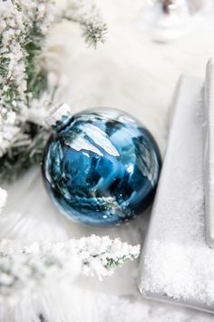 a blue ornament sitting on top of snow covered ground next to a laptop