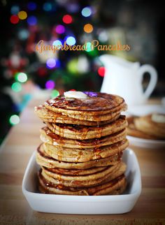 a stack of pancakes sitting on top of a white plate next to a christmas tree