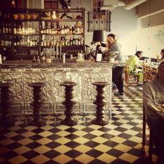 people sitting at tables in a restaurant with black and white checkerboard flooring