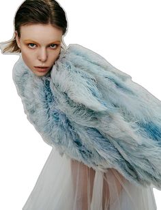 a woman wearing a blue and white fur coat over her shoulders, looking at the camera