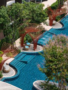 an aerial view of a swimming pool surrounded by trees and plants in the foreground