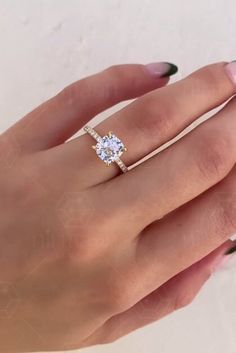 a woman's hand holding a ring with a diamond on it and the middle finger