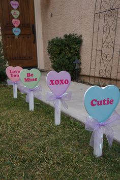 three heart shaped candy boxes sitting on top of grass next to a house with decorations