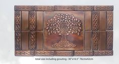 an intricately designed metal plaque with a tree on the front and sides, is shown