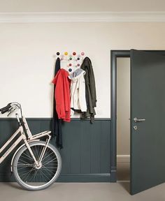 a bicycle is parked in front of a wall with coat racks and coats on it