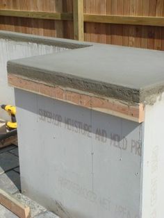 a concrete slab is being built in front of a wooden fence