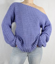 a woman is wearing a purple sweater with an off the shoulder design on her shoulders