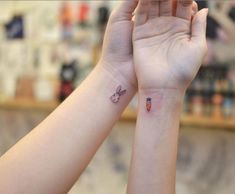 two people with matching tattoos on their arms holding each other's hands in the air