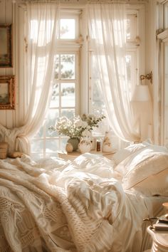 a white bed sitting next to a window in a room with curtains on the windowsill