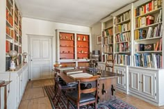 a room filled with lots of bookshelves next to a dining table and chairs