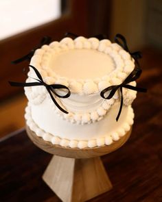 a three tiered white cake with black bows on it's top and bottom