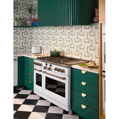 a green and white kitchen with an oven in the center, cabinets on both sides