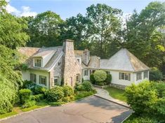 an aerial view of a large home surrounded by trees and greenery with a driveway leading to the front door