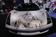 a white car with an artistic design on it's hood is parked in a showroom