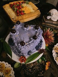 a blue cake sitting on top of a white plate next to other cakes and desserts