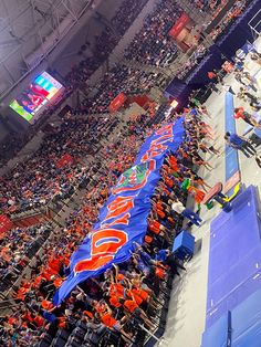 an orange and blue banner is in the middle of a large stadium filled with people