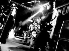 black and white photo of band playing on stage with microphones in front of them