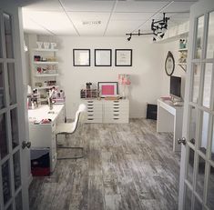 an office with white desks and shelves filled with personal items on the wall, along with open doors leading to another room