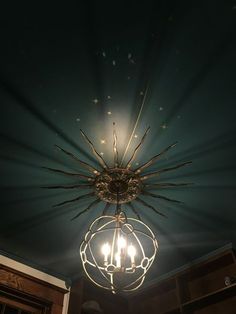 a chandelier hanging from the ceiling in a room with blue walls and wooden cabinets