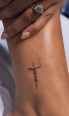 a woman's foot with a cross tattoo on it