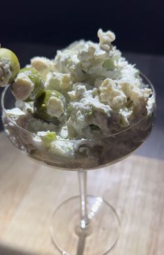 a dessert dish with grapes and cream in a wine glass on a wooden table top