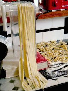 pasta being cooked in a blender on top of a kitchen counter next to a stack of uncooked noodles