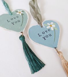 two heart shaped tags with tassels attached to them