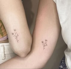 two people with matching tattoos on their arms, one holding the other's arm