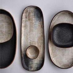 three wooden spoons with black and white plates in the shape of oval shapes, on top of each other