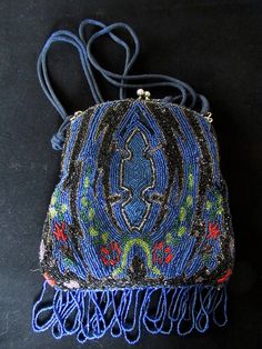 a small purse with beading and fringes on the front, sitting on a black surface